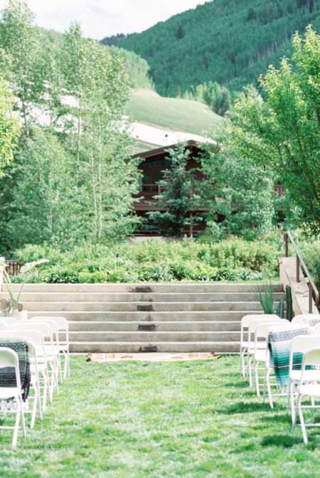 Mountain wedding ceremony set up with white chairs, blankets and a mountainous view.