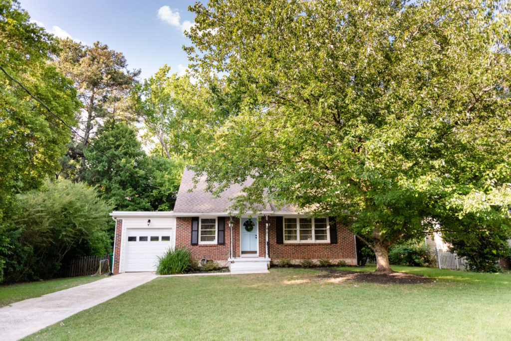 Cute house with pale blue front door, shutters, white garage door, lawn, trees