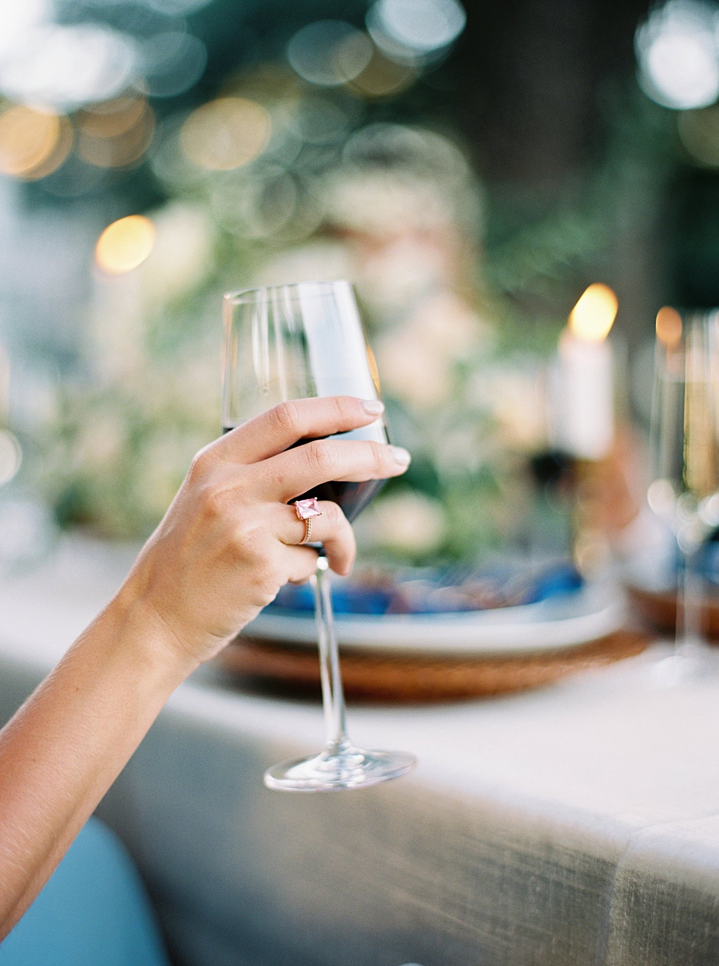 Glass of red wine being held at outdoor wedding reception