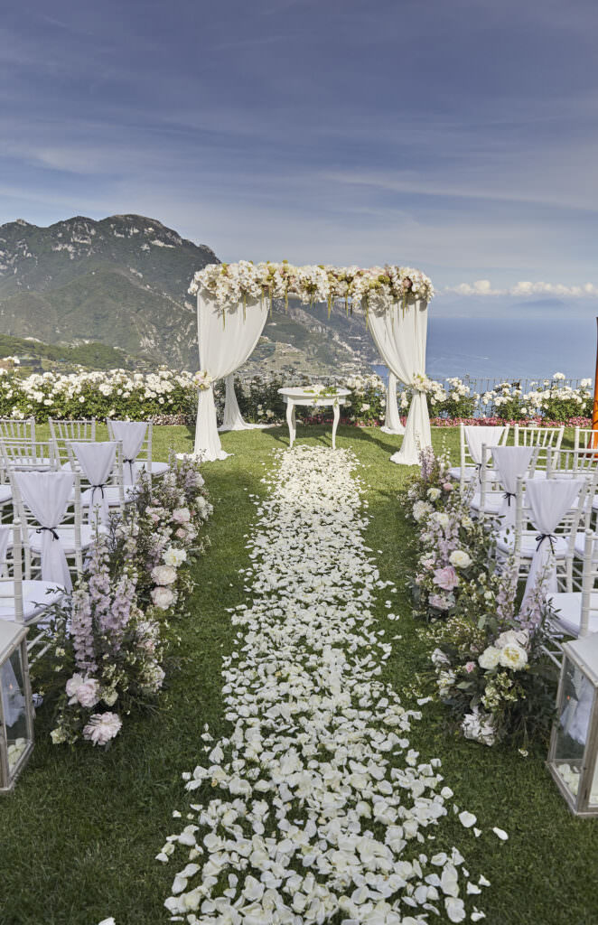 Wedding ceremony set up, with rose petal aisle, chairs and florals and a wedding arch. How to get married in Europe.