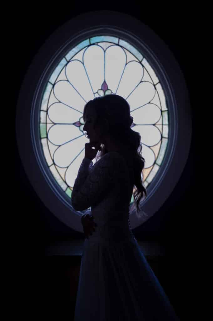 Bride by a stained glass window, captured by Perla Images, New England Wedding Photographers