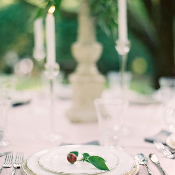 Wedding table set up with candles, elegant plates and silver flatware